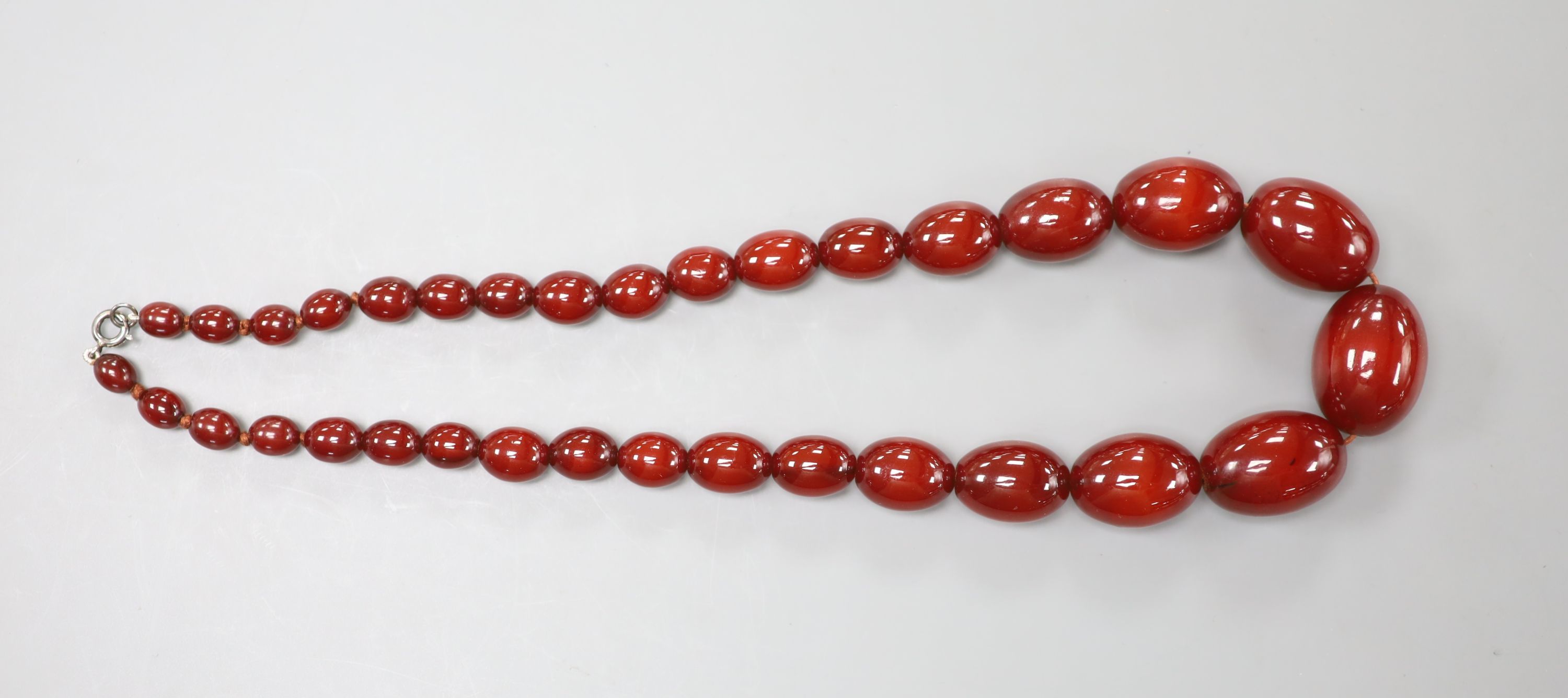 A single strand simulated oval amber bead necklace, 52cm and a pair of similar earrings, gross 94 grams.